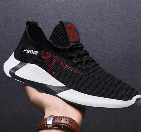 Black and white athletic shoe with red accents held by a person against a dark background