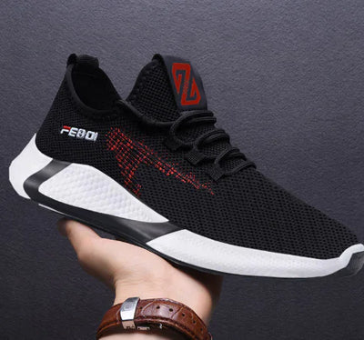 Black and white athletic shoe with red accents held by a person against a dark background