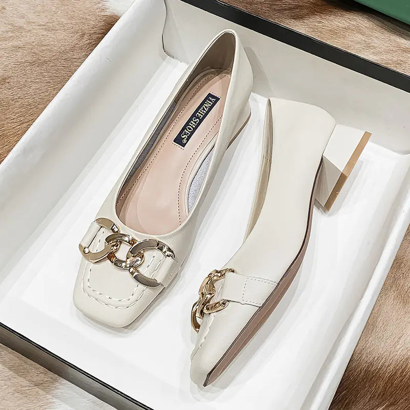 White shoes with gold chain detail on a white box
