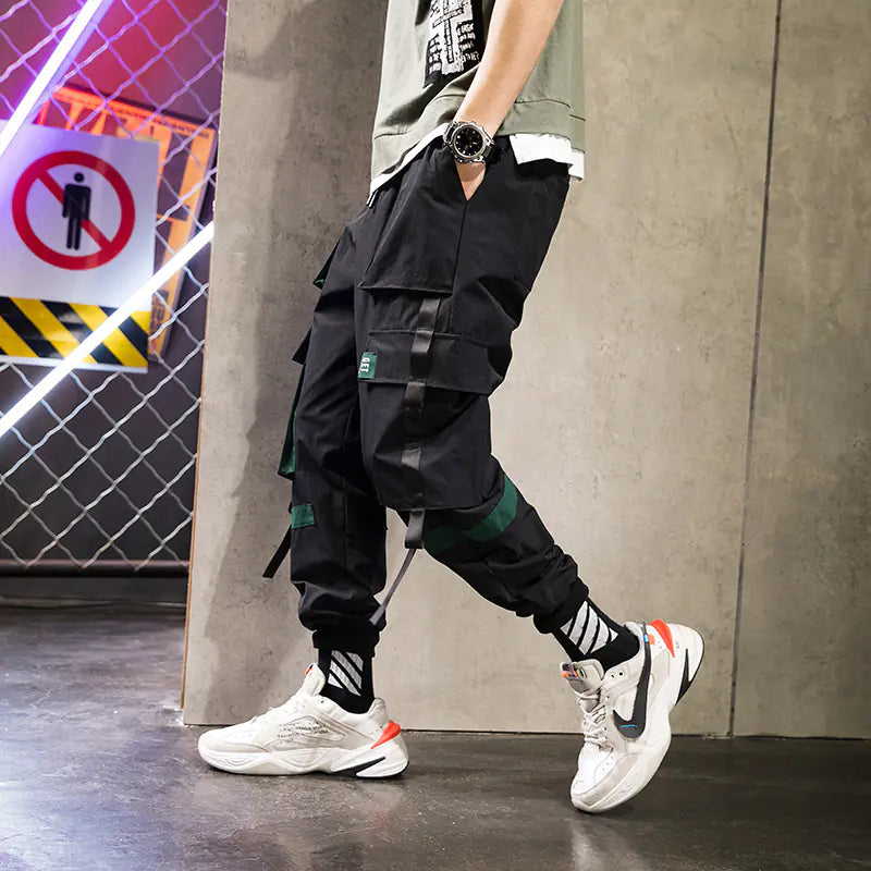 Person wearing black cargo pants and white sneakers in an urban setting.