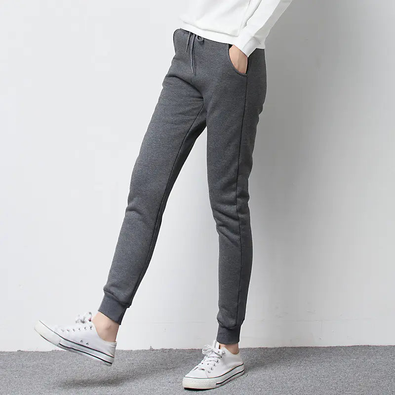 Person wearing gray fleece jogger pants and white sneakers on a plain background