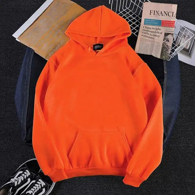 Orange hoodie on a dark surface with a newspaper and sneaker in the background