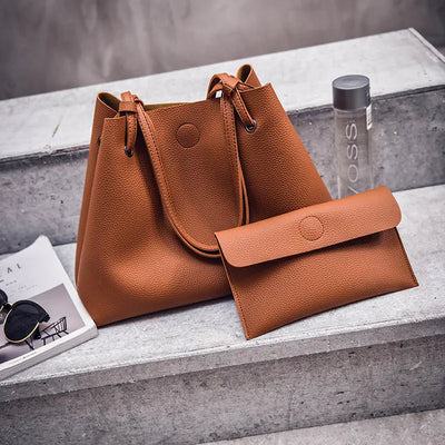 Brown leather handbag and wallet on a concrete surface with a blurred background
