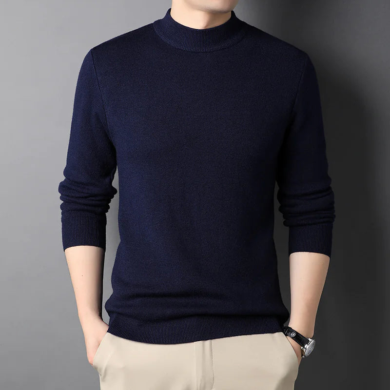 Person wearing a navy blue sweater against a gray background