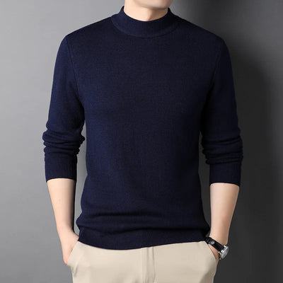 Person wearing a navy blue sweater against a gray background