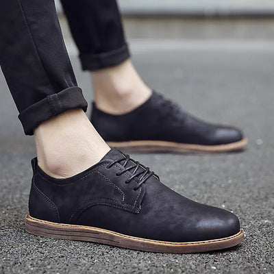 Black leather shoes worn on a concrete surface