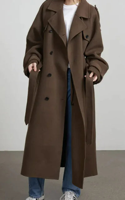 Person wearing a long brown coat on a plain background