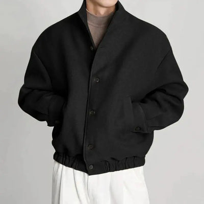 Person wearing a black jacket on a plain background