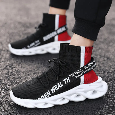 Black and red sneakers with white soles worn by a person on a textured surface.