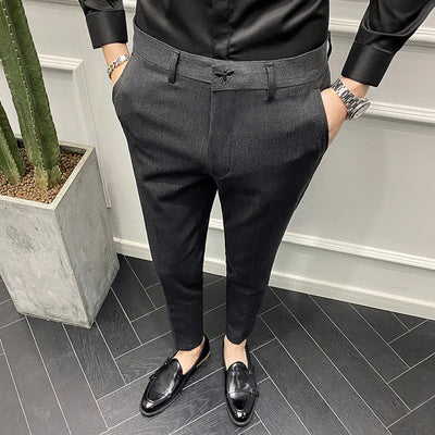 Person wearing black dress shoes on a gray floor with a plant in the background