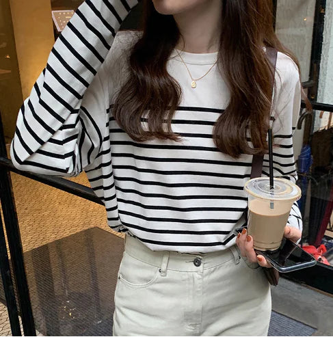 Person wearing a black and white striped shirt holding a drink.