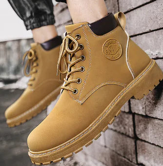 Tan boots with brand logo on a brick wall background