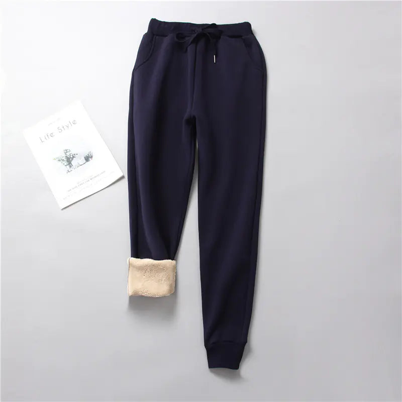 Navy blue jogger pants with beige cuffs on a light gray background