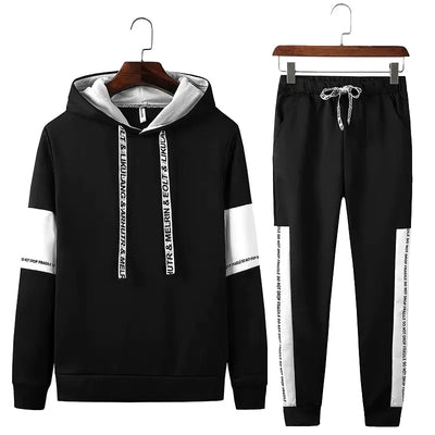 Black hoodie and pants set with white stripes and text on hangers against a white background