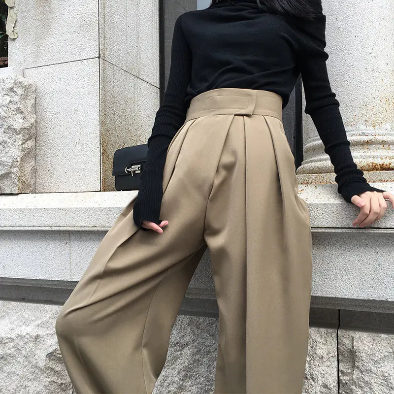 Person wearing beige wide-leg pants and a black top on stone steps.
