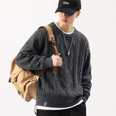 Person wearing a gray cable knit sweater with a beige backpack on a white background